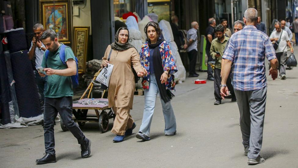 Pedestrians walking along a shaded street in Tehran
